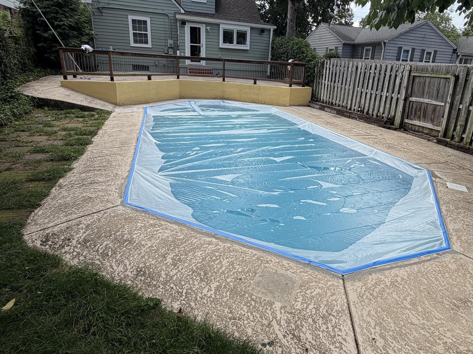 Worn, stained bare concrete pool deck before resurfacing