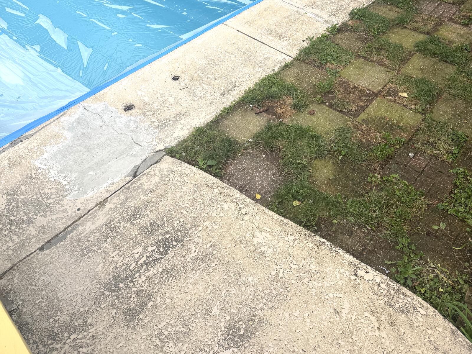 Close view of the original pool deck showing surface pitting and staining